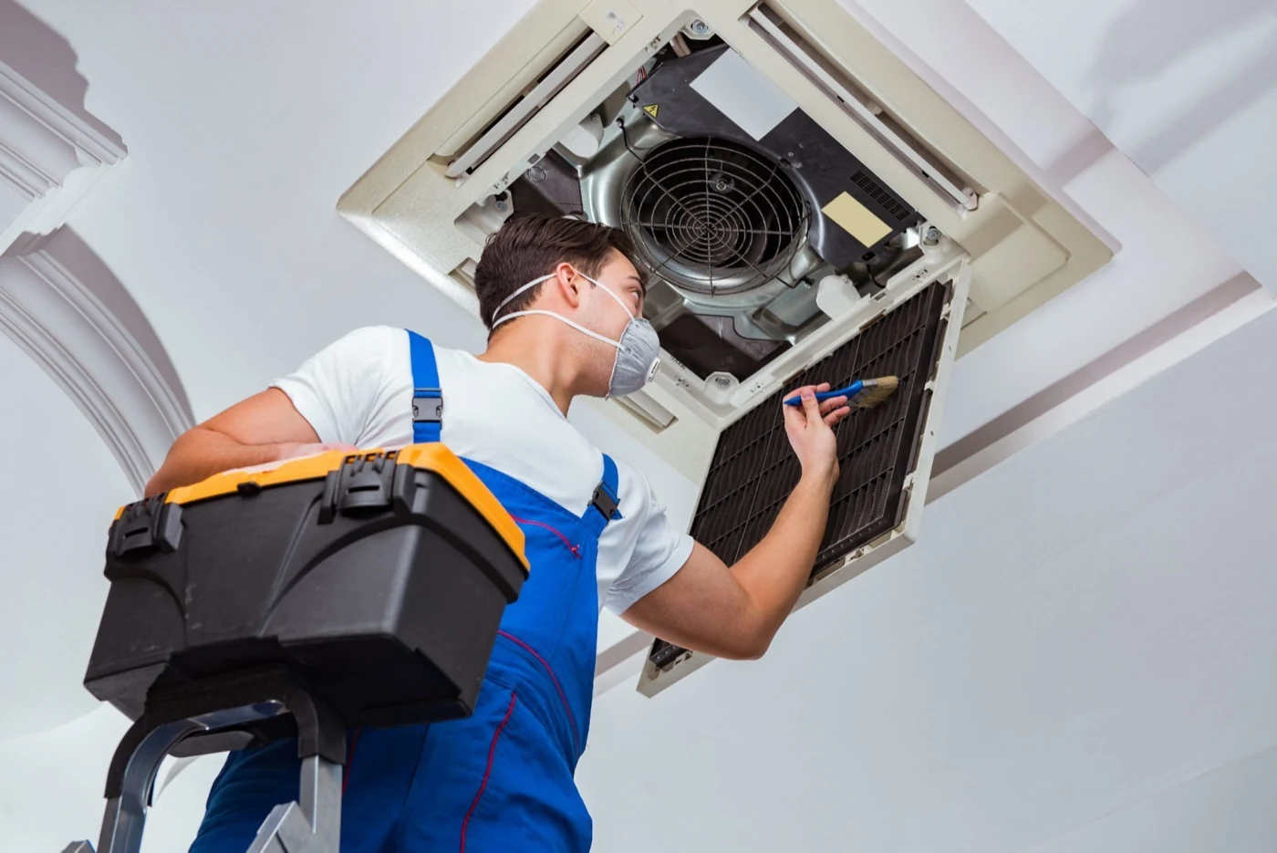 Technician servicing the filter of a ceiling-mounted HVAC unit
